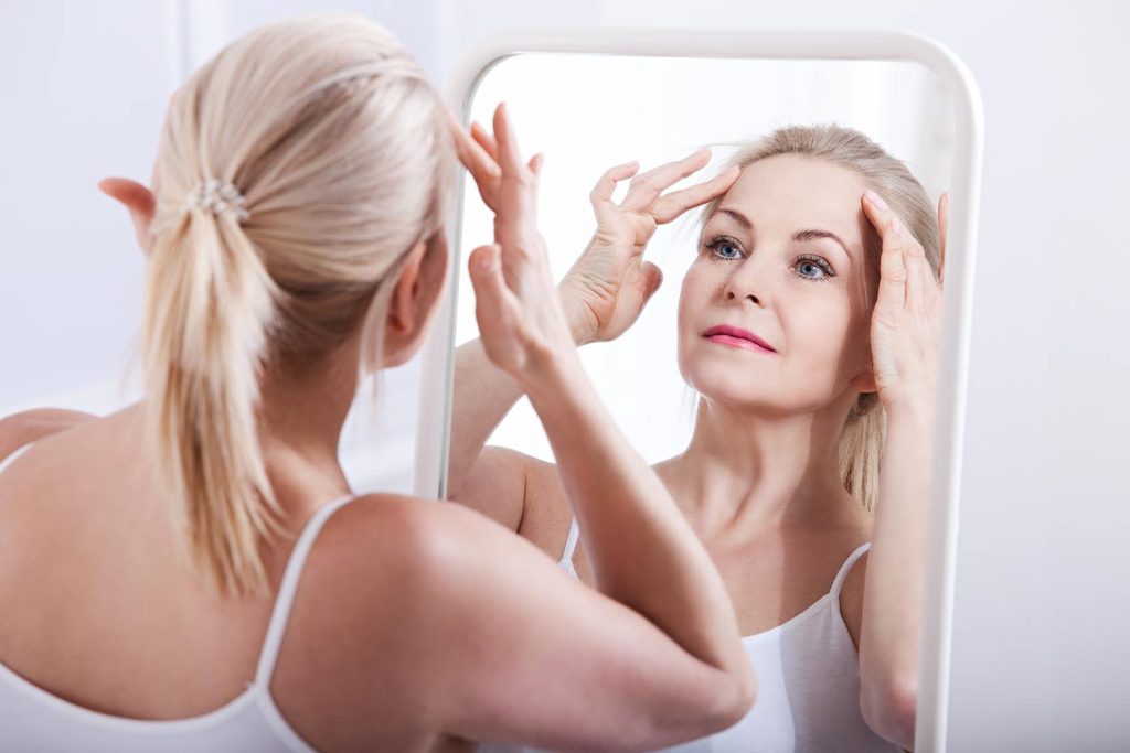 Woman admiring her face.  Facial Fat Transfer Dr. Zarrabi. 